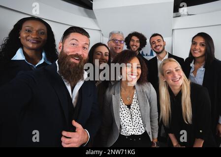 Portrait de selfie avec un grand groupe mixte de collègues élégants souriant et regardant l'appareil photo. Banque D'Images