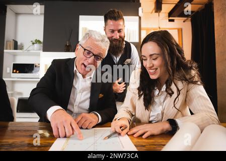 Groupe de trois collègues en gros plan sur le travail. Manager senior pointant un graphique et expliquant une stratégie. Banque D'Images