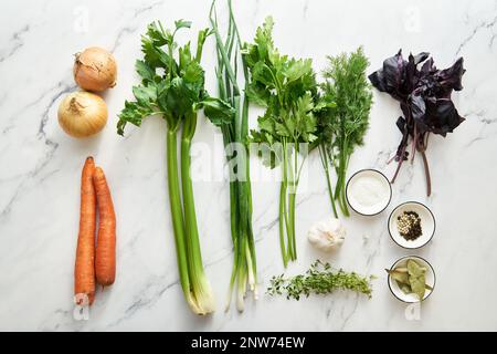 Ingrédients du bouillon de légumes sur fond blanc. Oignons et carottes plus verts comme oignons verts, basilic et thym. Poireaux et céleri Banque D'Images