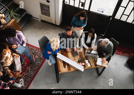 Vue de dessus équipe mixte de collègues travaillant dans un bureau moderne, assis à un bureau. Banque D'Images