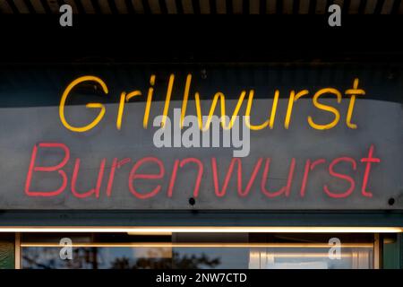 Gros plan sur une lumière au néon rouge en forme de mots allemands « Grillwurst » et « Burenwurst ». Banque D'Images