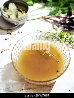 Bouillon de légumes dans un bol en verre. Ingrédients du bouillon sur le fond Banque D'Images