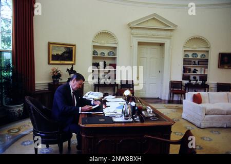 Le président Ronald Reagan travaillant à son bureau dans le Bureau ovale. noye les accessoires m'ont été donnés pour participer à un projet minute dans la vie du monde. Photographie de Dennis Brack BB87 Banque D'Images