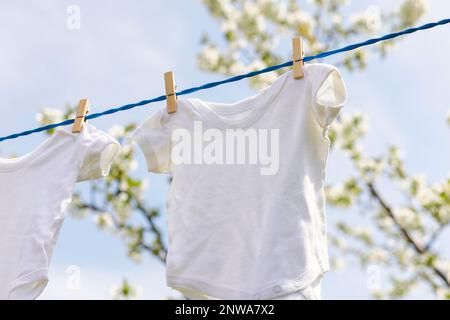 Vêtements pour enfants accrochés à la ligne de vêtements parmi les pommiers en fleurs dans le jardin Banque D'Images