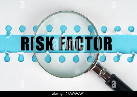 Entre deux feuilles d'un carnet sur une bande bleue avec l'inscription - FACTEUR DE RISQUE, il y a une loupe. Concept médical. Banque D'Images
