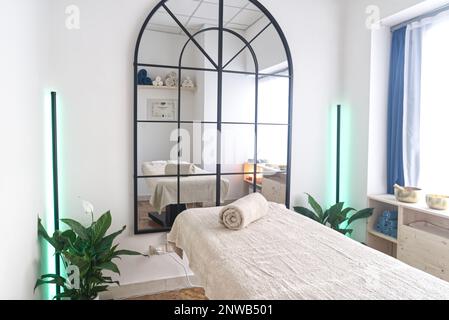 Salle de massage intérieur confortable avec un grand miroir devant la table de massage Banque D'Images