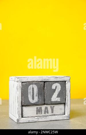 2 mai, sur calendrier fait bois peint en gris et blanc, fond jaune Banque D'Images
