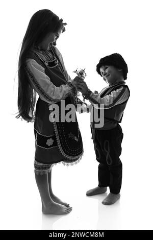 Garçon bulgare enfants, fille en costumes ethniques folkloriques, bouquet de fleurs de printemps neige, laine martenitsa symbole de Mars Baba Marta vacances, Bulgarie Banque D'Images