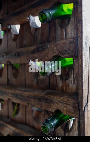 Vieux porte-marionnettes en bois pour bouteilles de champagne avec bouteilles vides vertes comme décoration extérieure dans le jardin Banque D'Images