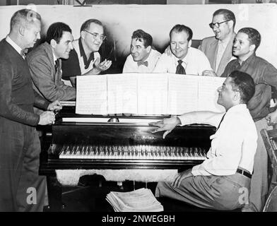 Benny Goodman (troisième à partir de la gauche) avec certains de ses anciens musiciens, assis autour du piano de gauche à droite : Vernon Brown, George Auld, Gene Krupa, Clint Neagley, Ziggy Elman, Israel Crosby et Teddy Wilson (au piano). Benjamin David Goodman (1909 – 1986) clarinettiste et chef de bande américain connu sous le nom de « roi de l'oscillation ». Banque D'Images