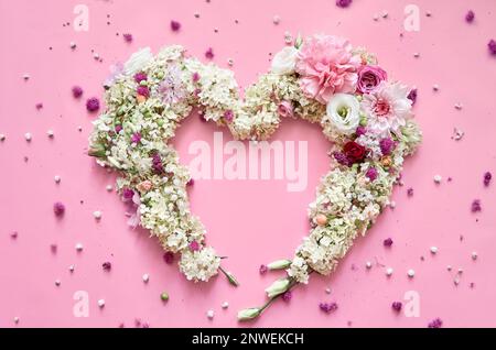 Fleurs pétales coeur sur fond rose floral pastel. Plan d'agencement, vue de dessus Banque D'Images