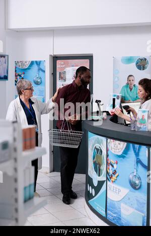 Client adulte mettant des produits pharmaceutiques sur le comptoir, se préparant à payer le traitement. Client afro-américain prenant des boîtes de médicaments et des suppléments de pharmacie, service de médecine Banque D'Images