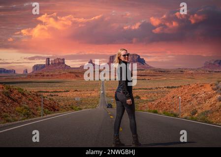 Emblématique Monument Valley en Arizona, Utah pendant l'été, au cours d'un coucher de soleil rose après-midi avec autoroute droite menant à de célèbres formations rocheuses. Banque D'Images