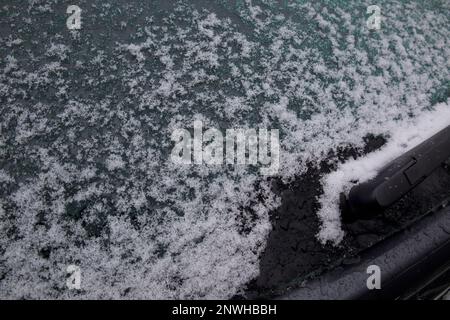 Gros plan de l'arrière, de la vitre de voiture après la neige, la grésil et la tempête de verglas en Nouvelle-Angleterre. La photo montre une partie de l'essuie-glace arrière et de la voiture grise Banque D'Images