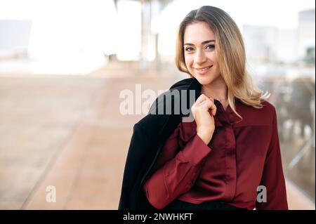 Portrait d'une belle femme d'affaires confiante, une femme d'affaires réussie, pdg de la société, directeur financier ou directeur des RH, dans des vêtements élégants, debout à l'extérieur, regardant l'appareil photo, souriant Banque D'Images