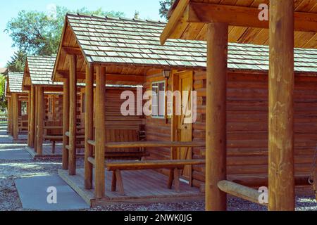 Les chalets en rondins d'une rangée ont des promenades en ciment, des porches et des balançoires. Il y a des cabines de location fermées pour la saison. Les toits sont agréables et les portes et les fenêtres sont fermées. Banque D'Images