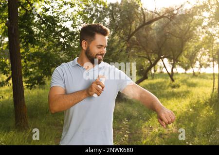 Homme appliquant un insectifuge sur le bras dans le parc. Prévention des piqûres de tiques Banque D'Images