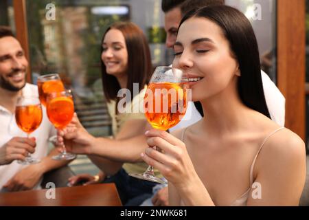 Amis passant du temps ensemble, concentrez-vous sur la jeune femme qui boit le cocktail Aperol spritz Banque D'Images