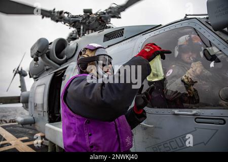 MER BALTIQUE (24 janvier 2023) technicien en systèmes de turbines à gaz (mécanique) 3rd classe Joshua Ferdinand présente un échantillon de carburant au Lt. Cmdr. Francis Atkinson dans un hélicoptère MH-60R Seahawk, attaché à l'escadron de frappe maritime (HSM) 79, sur le pont de vol du destroyer USS Roosevelt (DDG 80) de la classe Arleigh Burke, le 24 janvier 2023. Roosevelt est en cours de déploiement aux États-Unis Marine Forces Europe zone d'opérations, employée par les États-Unis Sixième flotte pour défendre les intérêts des États-Unis, des alliés et des partenaires. Banque D'Images