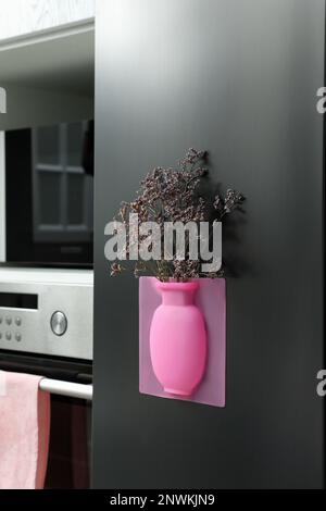 Vase en silicone avec de belles fleurs violettes sur le réfrigérateur dans la cuisine Banque D'Images