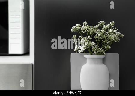 Vase en silicone avec de belles fleurs de gitsophila au réfrigérateur dans la cuisine, espace pour le texte Banque D'Images