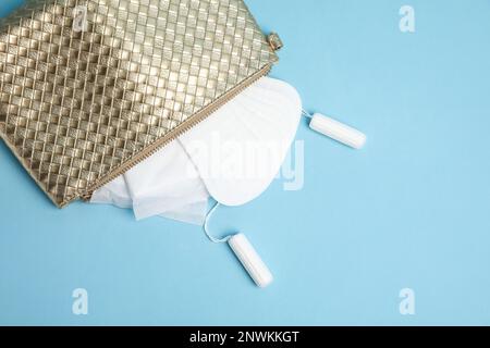 Sac avec tapis menstruels, tampons et pantyliners sur fond bleu clair, couché à plat Banque D'Images