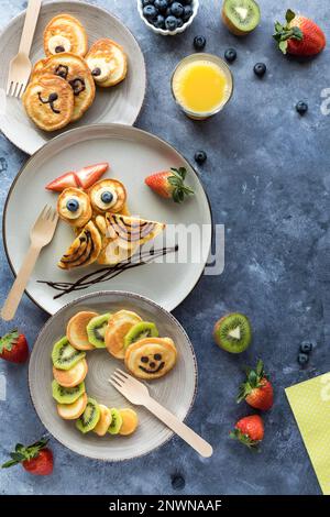 Crêpes aux formes de créatures, servies avec des fruits et du jus pour les enfants. Banque D'Images