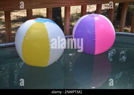 Deux ballons de plage gonflés flottant dans un réservoir de stockage. Un endroit rafraîchissant pour se rafraîchir par une chaude journée d'été. Banque D'Images