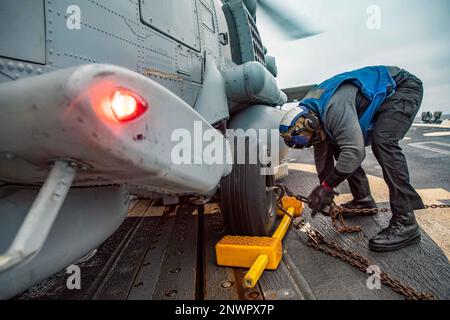 MER BALTIQUE (24 janvier 2023) le spécialiste des services de détail 2nd classe Jakerion Brown applique des chaînes à un hélicoptère MH-60R Seahawk, attaché à l'escadron de frappe maritime (HSM) 79, sur le pont de vol du destroyer à missiles guidés de classe Arleigh Burke USS Roosevelt (DDG 80), 24 janvier 2023. Roosevelt est en cours de déploiement aux États-Unis Marine Forces Europe zone d'opérations, employée par les États-Unis Sixième flotte pour défendre les intérêts des États-Unis, des alliés et des partenaires. Banque D'Images