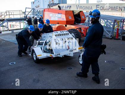 Les marins chargent des chariots à azote et d'autres équipements à bord du porte-avions de la classe Nimitz USS George Washington (CVN73) pour le département de maintenance intermédiaire de l'aviation à Newport News, Virginie, le 24 janvier 2023. George Washington est en cours de ravitaillement et de révision complexe (RCOH) à Newport News Shipbuilding. Le RCOH est un projet pluriannuel exécuté une seule fois au cours de la durée de service de 50 ans d’un transporteur, qui comprend le ravitaillement en carburant des deux réacteurs nucléaires du navire, ainsi que des réparations, des mises à niveau et une modernisation importantes. Banque D'Images