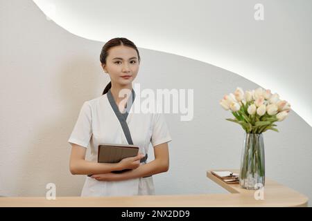 Jeune cosmétologue avec tablette numérique debout à la réception du salon de spa Banque D'Images