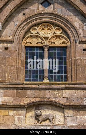 Détail de la façade avec une fenêtre à meneaux et un lion en relief, de l'ancienne église de San Leonardo. Tuscania, province de Viterbo, Latium, Italie Banque D'Images