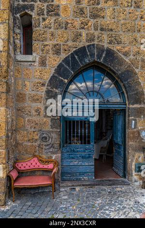 Ancienne porte médiévale avec une arche pointue peinte en bleu et un fauteuil rose à côté. Tuscania, province de viterbo, latium, italie, europe Banque D'Images