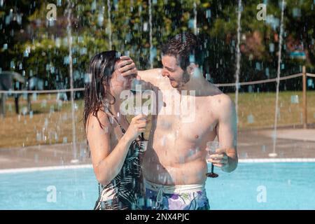 Jeune couple aimant se détendre et boire du vin dans l'hydromassage de la piscine. Concept de jeunes s'amuser en été Banque D'Images