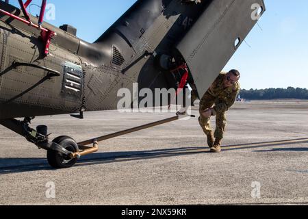 Un soldat de la division d'infanterie 3rd, une brigade de l'aviation de combat, 3rd, guide un UH-60 Blackhawk sur un C-17 Globemaster lors d'un entraînement de chargement aérien conjoint à l'aérodrome de l'armée de chasseurs, Géorgie, 10 janvier 2023. Les soldats ont travaillé avec des aviateurs des escadrons de transport aérien de 15th et 16th, à la base interarmées de Charleston, apprenant à charger et décharger deux BLACKHAWKS UH-60 sur le C-17 Globemaster. Banque D'Images