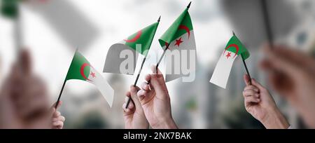 Un groupe de personnes tenant entre leurs mains de petits drapeaux de l'Algérie. Banque D'Images