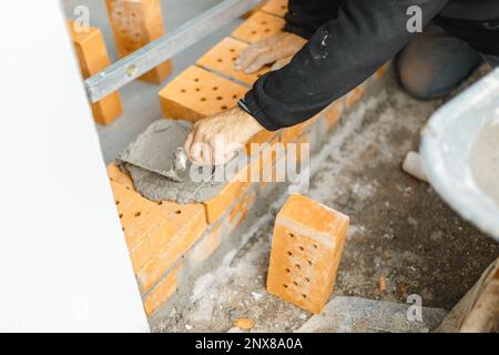 handyman enduisant le mur de briques de béton et de truelle Banque D'Images