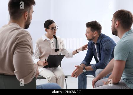 Psychothérapeute travaillant avec un groupe de personnes toxicomanes à la séance de thérapie à l'intérieur Banque D'Images