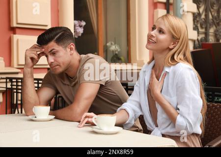 Homme ayant une date ennuyeuse avec une femme de parole dans un café en plein air Banque D'Images