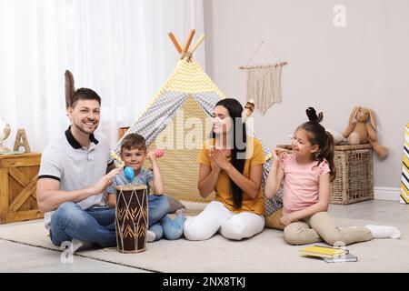 Bonne famille jouant ensemble à proximité de jouet wigwam à la maison Banque D'Images