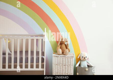 Intérieur mignon de la chambre d'enfant avec magnifique arc-en-ciel peint sur le mur Banque D'Images