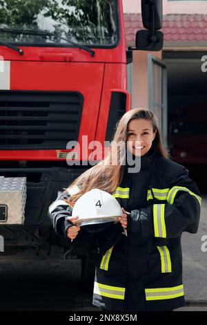 Portrait d'un pompier en uniforme avec un casque près d'un camion de pompiers à l'extérieur Banque D'Images