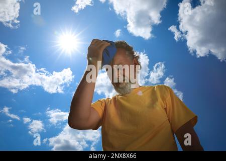 Homme âgé avec pack froid souffrant de coup de chaleur à l'extérieur, vue en angle bas Banque D'Images