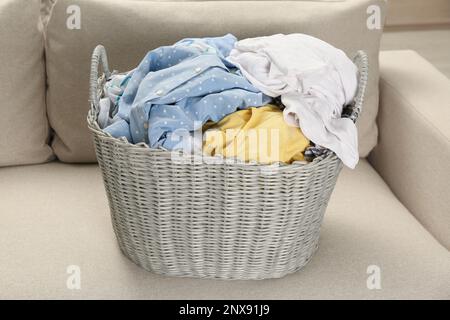 Panier en osier avec linge sale sur le canapé dans la chambre Banque D'Images