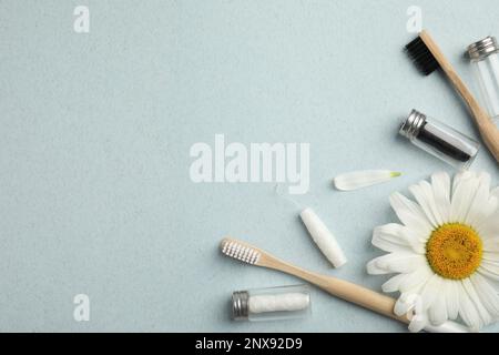 Composition de la couche plate avec des mousses dentaires biodégradables, des brosses à dents en bambou et de la camomille sur fond bleu clair. Espace pour le texte Banque D'Images