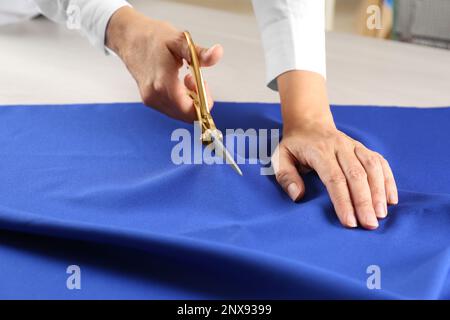 Couturière découpe du tissu à la table en atelier, gros plan Banque D'Images