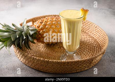 Lassi traditionnel asiatique aux ananas sur fond gris. Boisson fraîche froide à base de yaourt, eau, épices, fruits et glace. Boisson populaire en Inde Banque D'Images