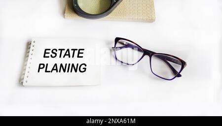 Bloc-notes avec texte Estate Planning sur fond blanc avec verres, loupe et agenda Banque D'Images