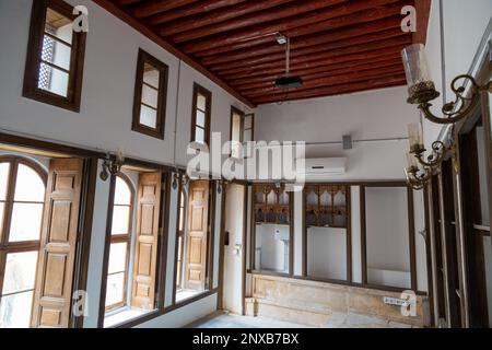 Vue intérieure d'une maison traditionnelle de Kilis (résidence de Mahmut Islam Bey), Turquie. Plafond en bois, fenêtres et étagères murales intégrées dans une pièce. Banque D'Images