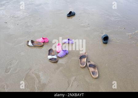 Vue en hauteur de cinq paires de sandales sur une plage en été Banque D'Images